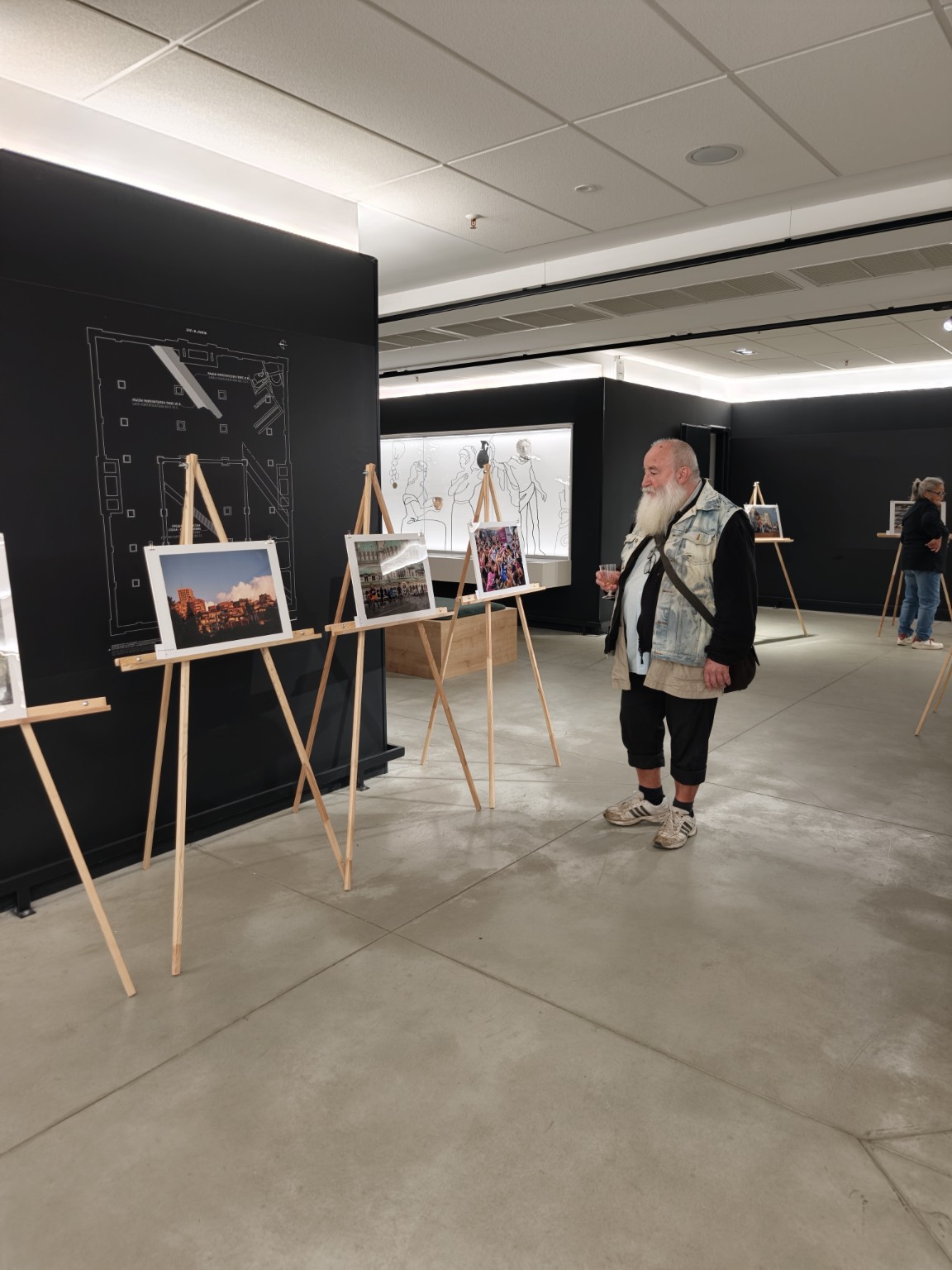 Фотографии на стативи и посетител в изложбеното пространство